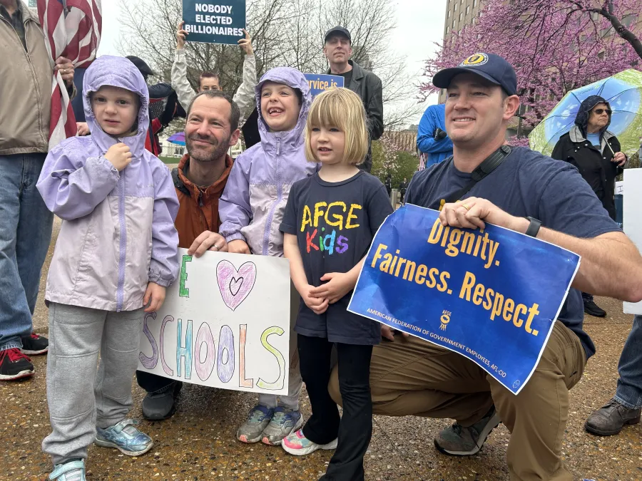 Members at an AFGE rally with their kids holding a sign saying "Dignity, Fairness, Respect." 